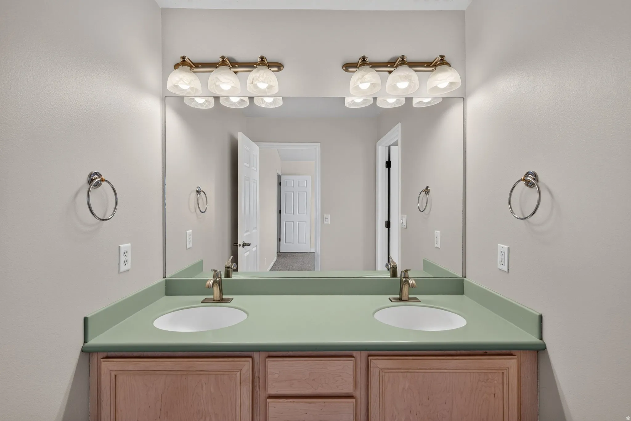 Dual vanity with integrated sinks, green countertop, wood-finish cabinetry, and brushed nickel fixtures