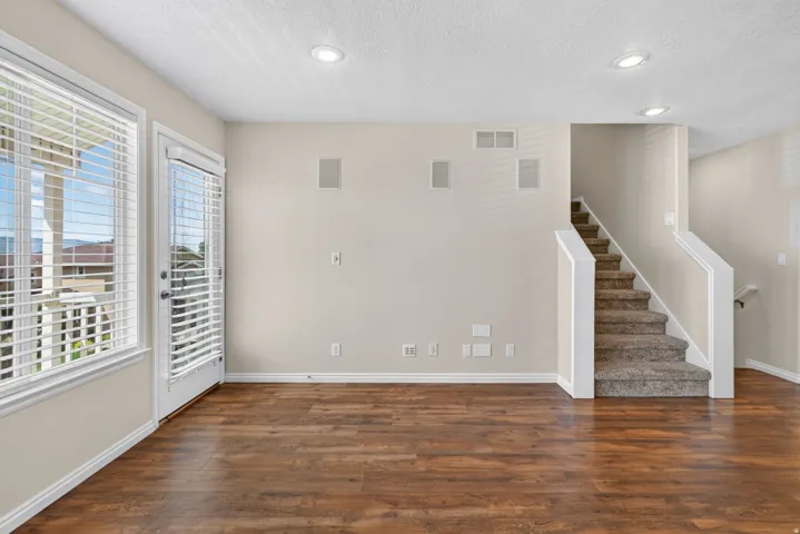 Wood-finish flooring, recessed ceiling lighting, built-in wall speakers, and a staircase with carpeted treads