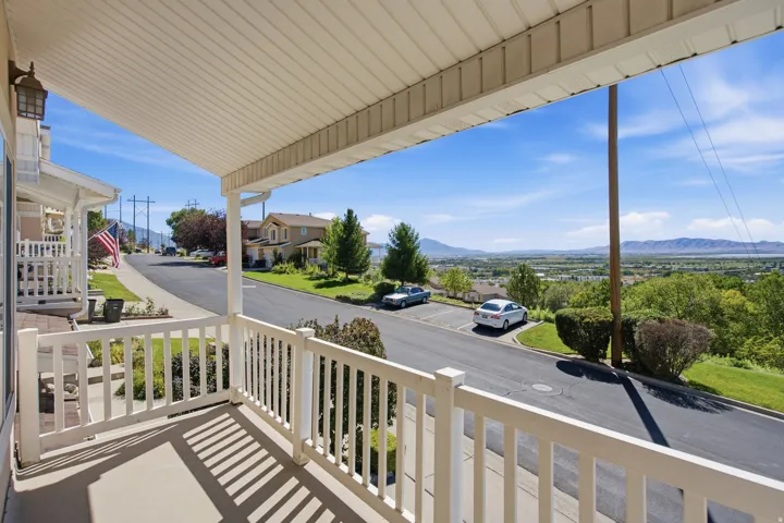 Covered front porch with white railings and a concrete floor