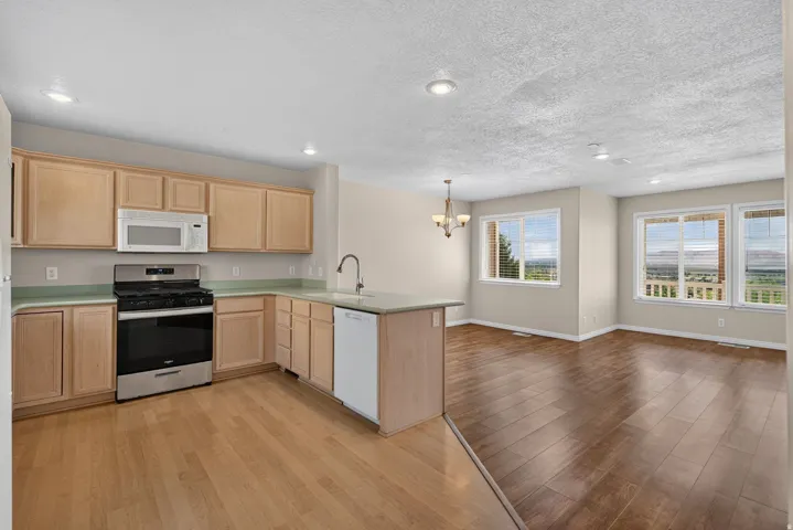 Kitchen featuring wood-finish cabinetry, stainless steel appliances, and a peninsula with integrated sink