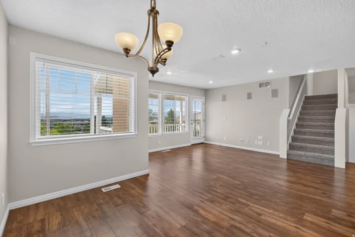 Wood-finish flooring, recessed ceiling lighting, a contemporary chandelier, and a carpeted staircase