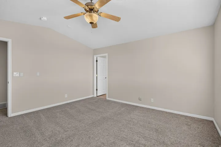 Carpeted room featuring a ceiling fan with light fixture and light-colored walls