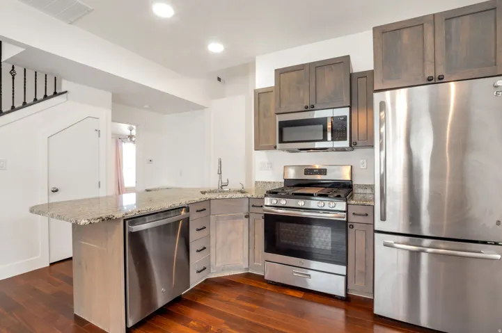 Stainless steel appliances, granite countertops, wood-finish flooring, recessed lighting, and dark wood cabinetry