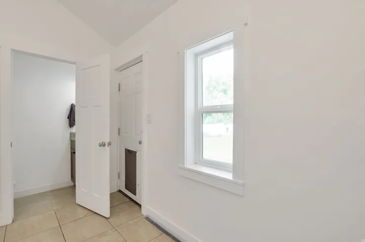White interior walls, tile flooring, interior panel door, exterior panel door, and a single-hung window