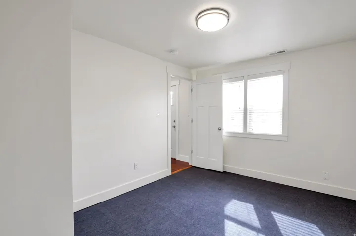 Carpeted flooring, white walls, and a window with blinds