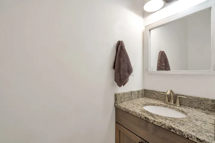 Vanity with a granite countertop, undermount sink, and brushed nickel faucet