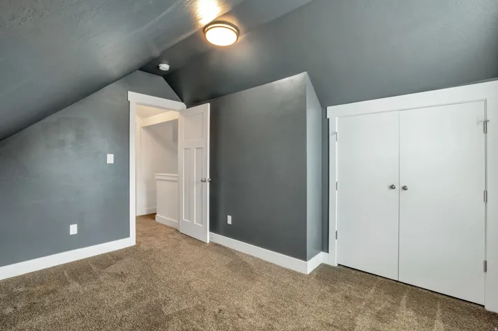 Spacious bonus room featuring vaulted ceilings with recessed lighting, neutral carpet flooring, and dual closets with white panel doors