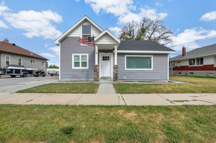 Light gray siding exterior with white trim, a gabled roofline, and a prominent front entrance featuring a white door