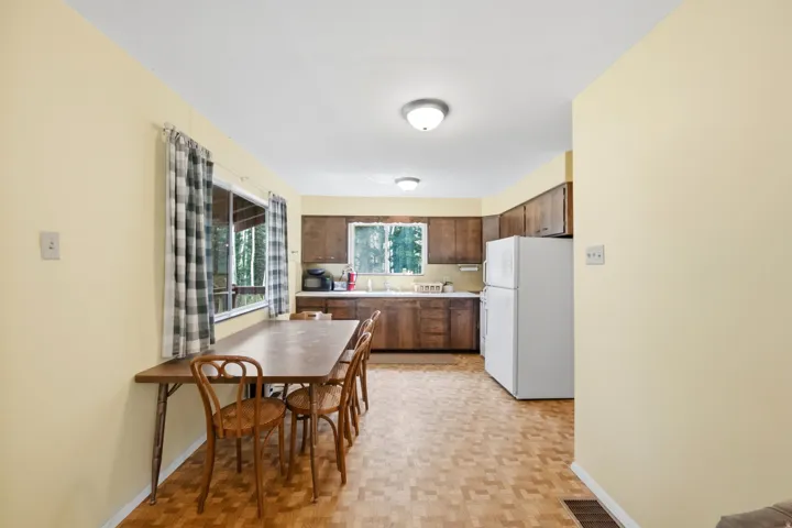 Kitchen dining area with a window providing outdoor visibility, wood cabinetry, and a built-in kitchen sink