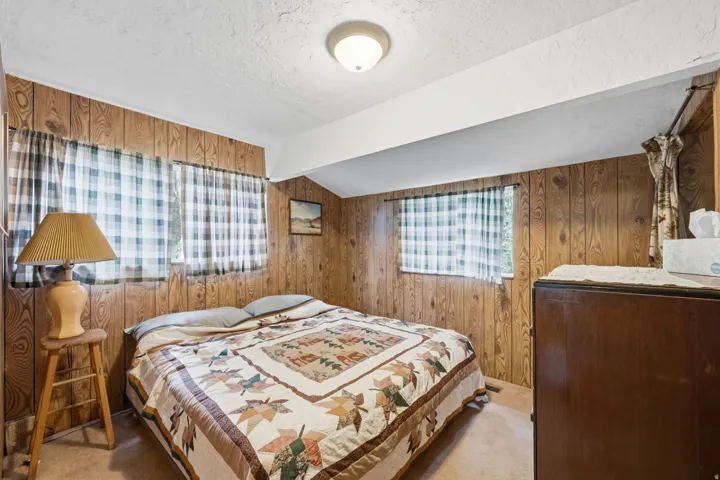 Wood-finish wall paneling, two windows with textile coverings, and a built-in overhead light fixture