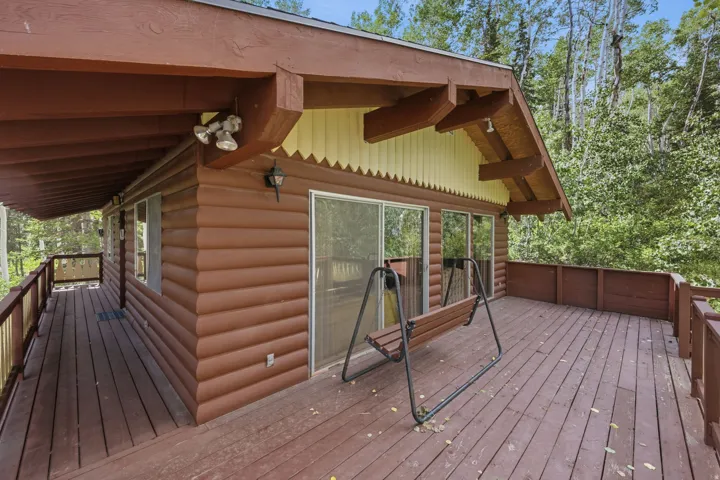 Expansive outdoor deck featuring wood flooring and railings, log cabin siding, and multiple sliding glass doors