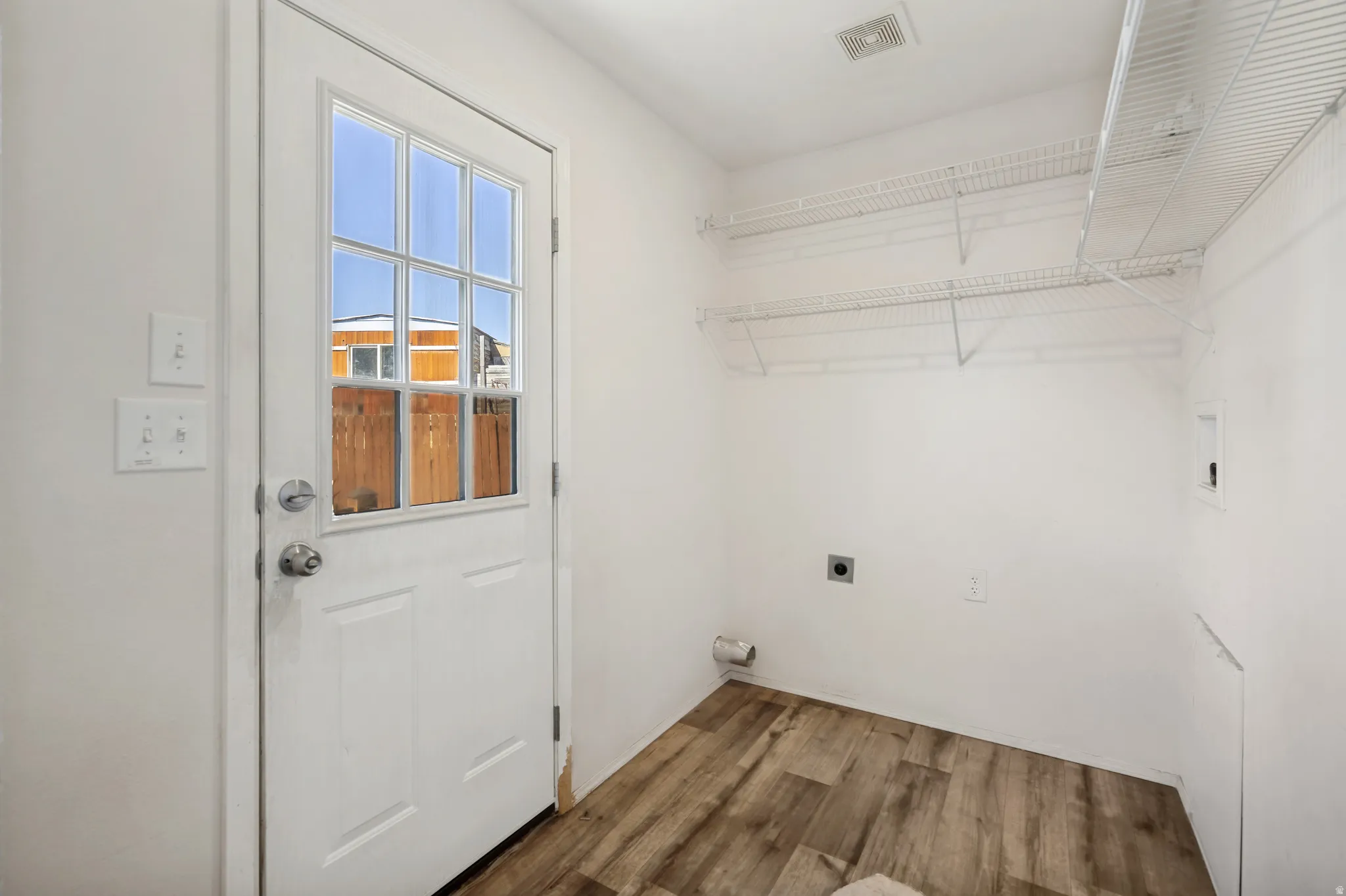 Wood-finish flooring with white walls and a white paneled door