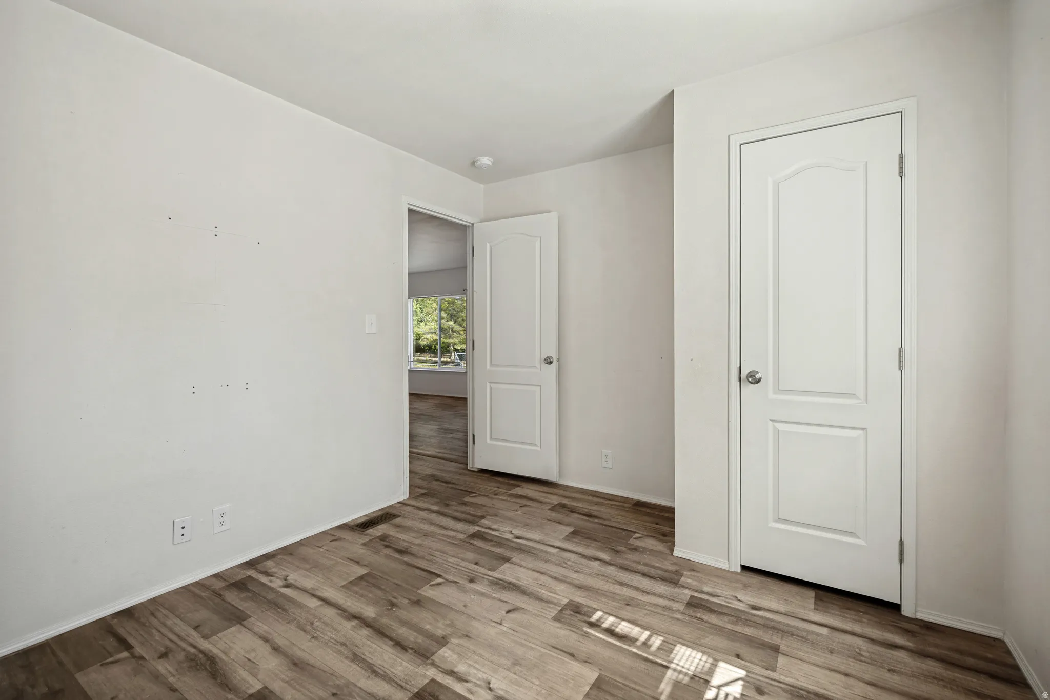 Wood-finish flooring throughout, white walls, and white interior doors