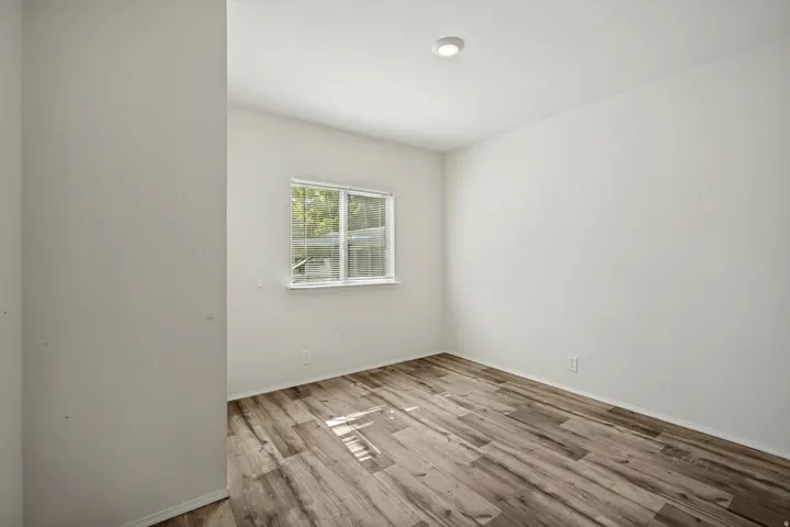 Recessed ceiling light, white painted walls, wood-finish flooring, and a white-framed window