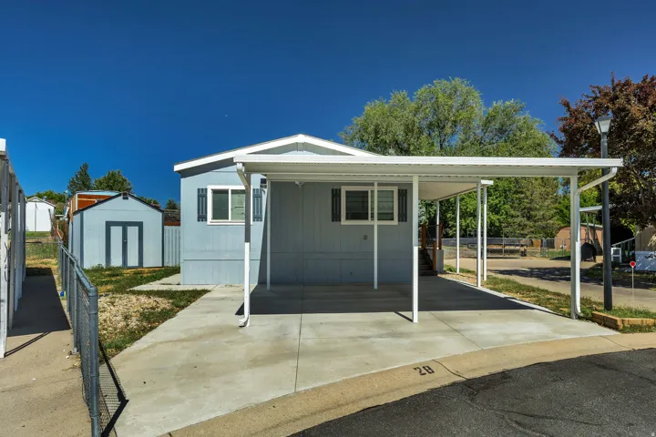 Exterior siding with white trim, covered carport, concrete driveway, storage shed, and a street lamp