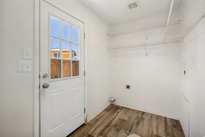 Wood-finish flooring with white walls and a white paneled door