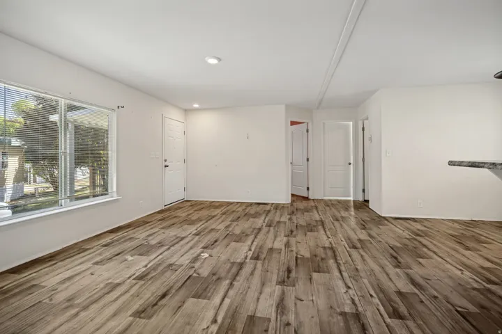 Open-concept living space featuring wood-finish flooring, recessed lighting, and a large front-facing window