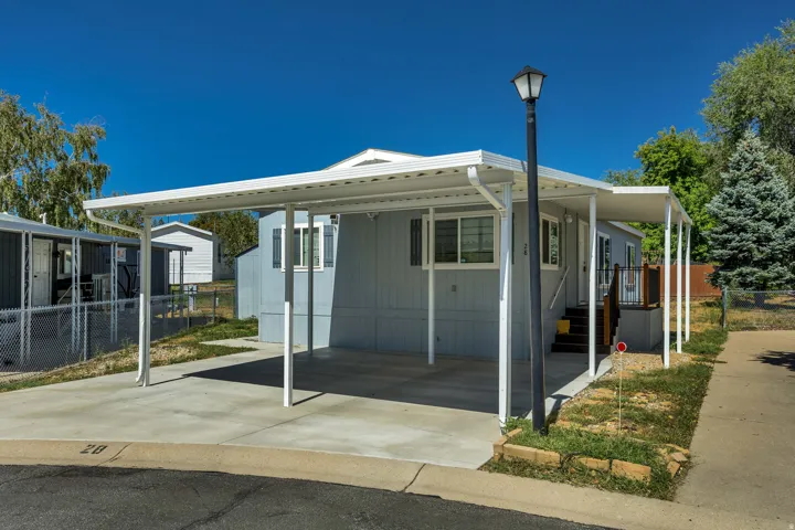 Carport with concrete pad, light blue exterior siding, white window trim, and a built-in porch light