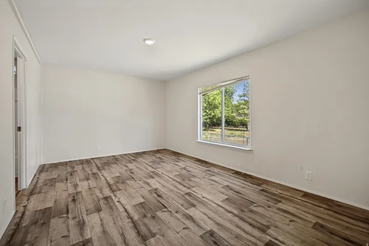 Wood-finish flooring, recessed ceiling light, white walls, and a large window with white trim