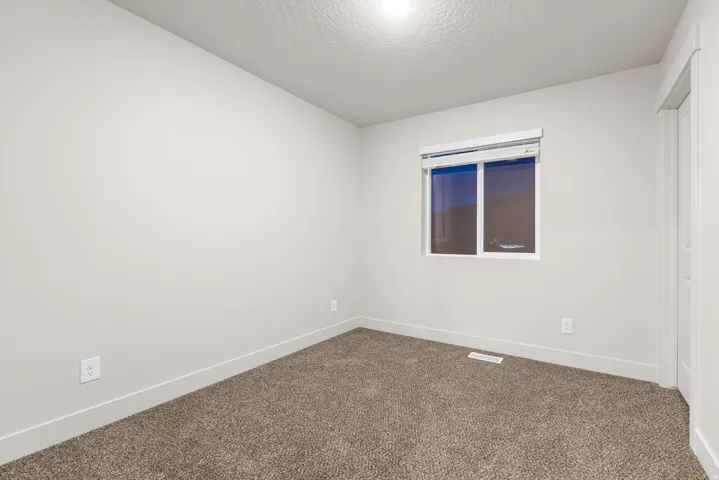 Neutral wall paint, carpet flooring, window with blinds, and white trim