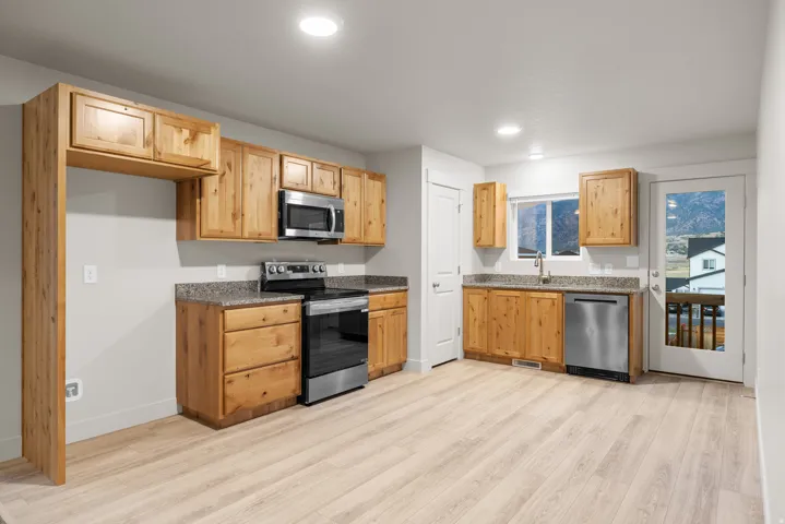 Kitchen featuring wood-finish cabinetry, stainless steel appliances, granite-style countertops, and wood-finish flooring