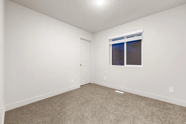 Neutral-toned carpeting, white interior paint, and a single-pane window with blinds