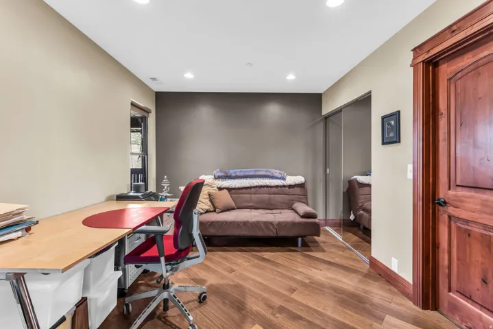 Wood-finish flooring, recessed lighting, wood-paneled door, mirrored closet doors, and contrasting accent wall