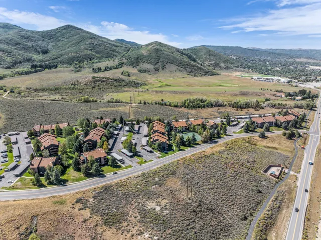 Expansive mountainous backdrop frames the community featuring multi-unit residences, extensive paved parking, and mature landscaping