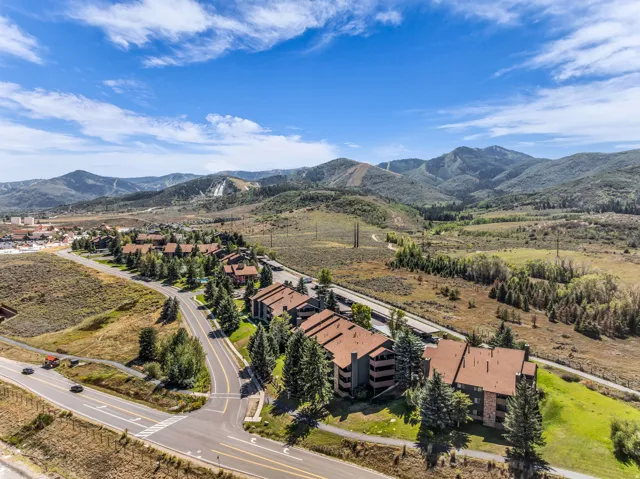 Mountain backdrop, residential buildings with brown roofs, paved roads, and evergreen trees