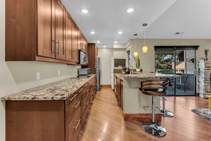 Kitchen featuring wood-finish flooring, recessed lighting, and a granite-finish countertop