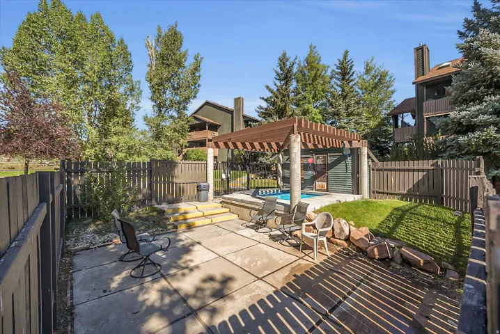 Outdoor patio with concrete pavers, fenced perimeter, and a built-in hot tub featuring a pergola cover