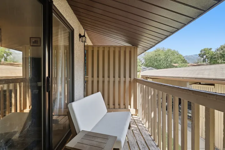 Balcony featuring wood decking, slatted railing, and a covered ceiling
