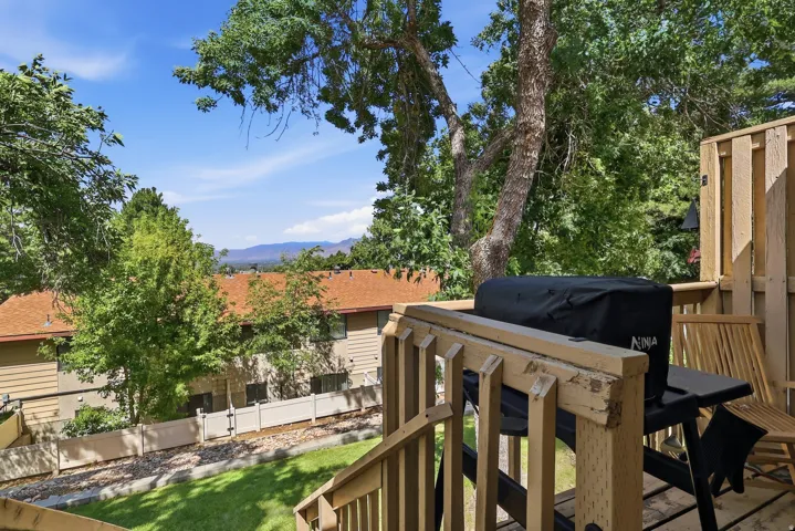 Outdoor deck featuring natural wood railing and a treed backdrop