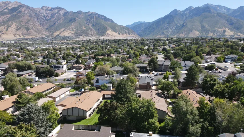 Mountain backdrop of Big Cottonwood Canyon with surrounding residential homes, lush green landscaping, and tree-lined streets.