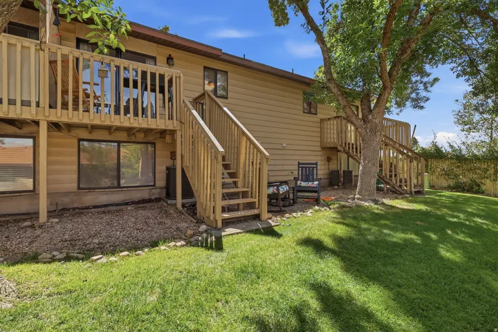 Common grassy off the deck and stairs featuring a green lawn, mature trees, and a multi-level wood deck with stairs
