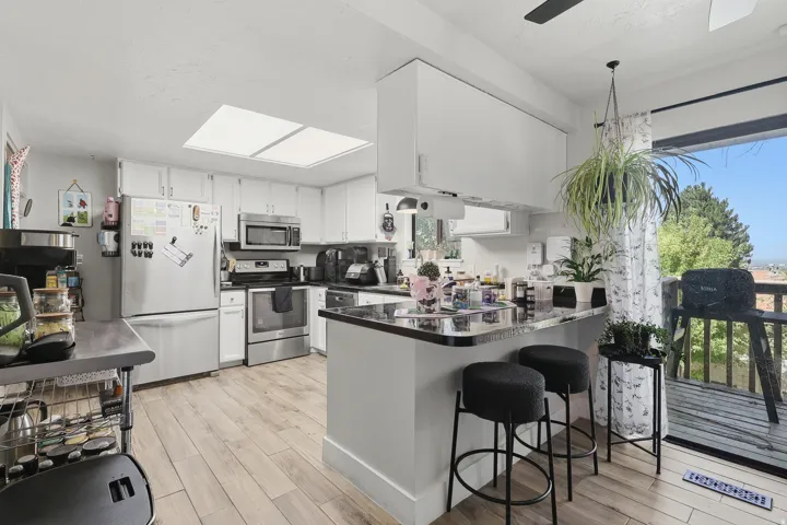 Kitchen with wood-finish flooring, white cabinetry, stainless steel appliances and direct access to an outdoor deck