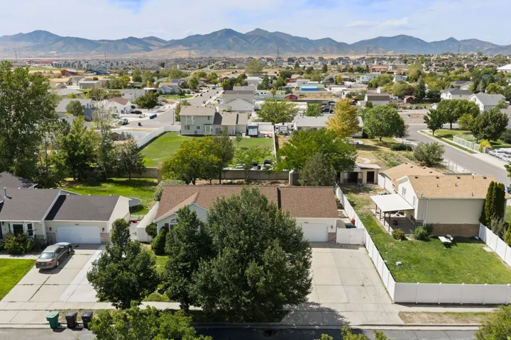 Mature landscaping, residential setting, mountain range backdrop, attached garage, paved driveway