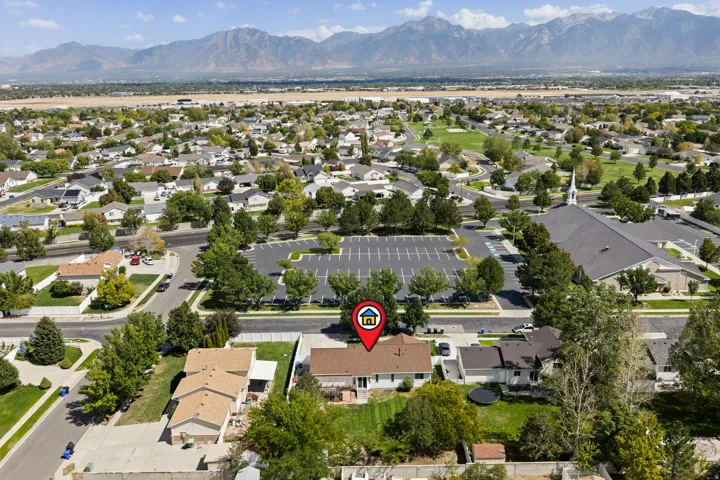 Mountain range backdrop, residential neighborhood setting, mature trees, paved streets, and adjacent community building
