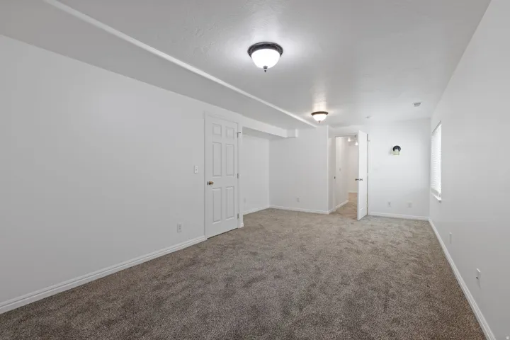 Neutral tone wall paint, textured ceiling, flush mount ceiling lights, paneled interior doors, and carpet flooring