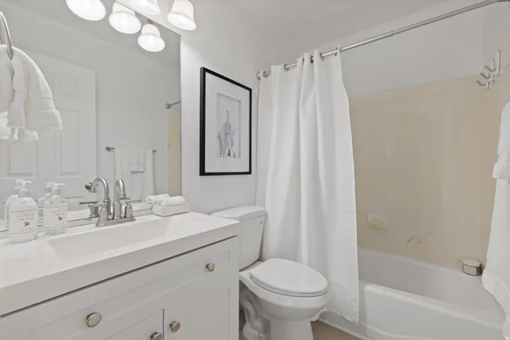 White vanity with dual doors and brushed nickel hardware, integrated sink, and chrome faucet