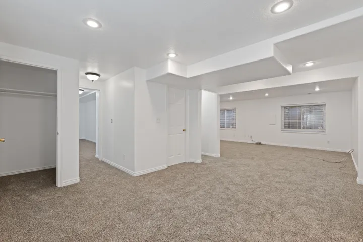 Spacious carpeted room featuring recessed lighting, multiple windows, and white painted walls
