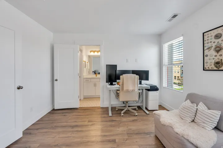 Wood-finish flooring throughout, white walls, and a window with horizontal blinds