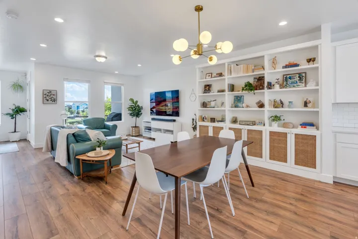 Wood-finish flooring, recessed lighting, built-in shelving with integrated cabinetry, modern chandelier, and multiple windows