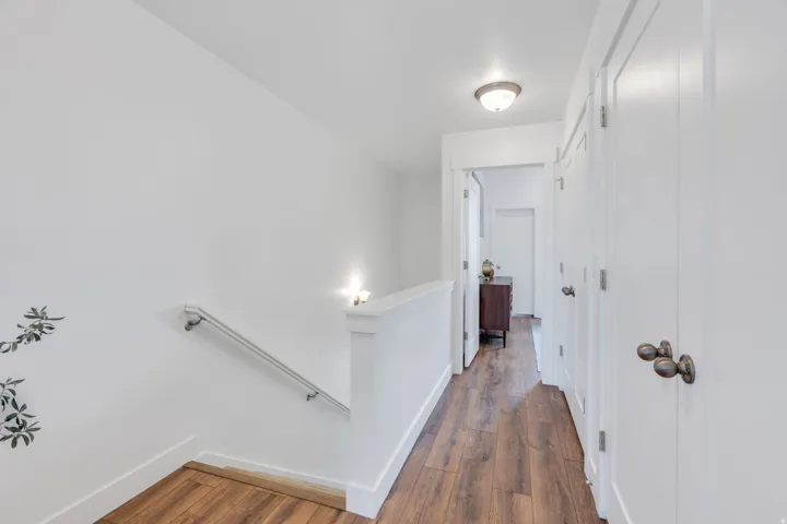 Hallway featuring wood-finish flooring, white walls, and bright overhead lighting