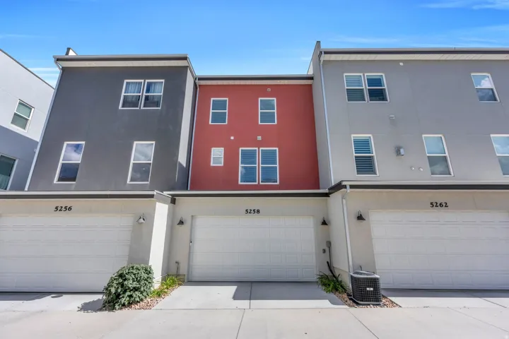 Multi-level townhouse exterior featuring a two-car garage, contemporary facade, and exterior lighting fixtures