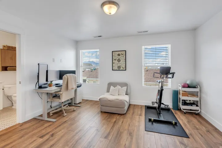 Expansive room featuring wood-finish flooring, white walls, and dual windows