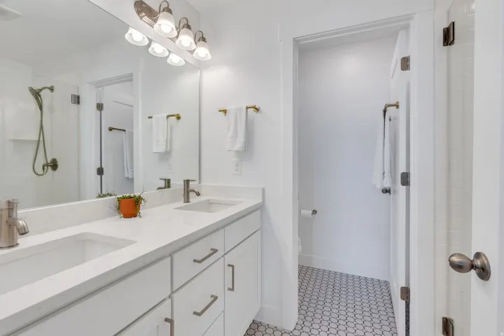 Dual vanity with integrated sinks, quartz countertops, white cabinetry, and brushed nickel hardware