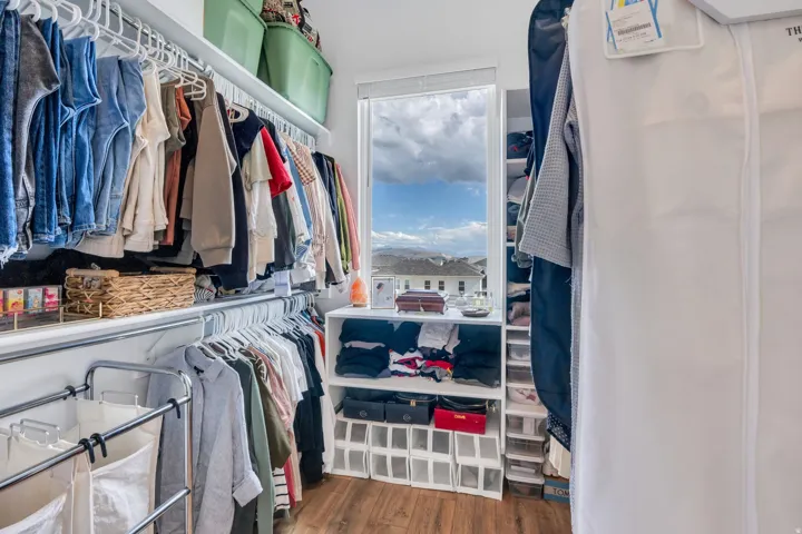 Built-in shelving with hanging rods, wood-finish flooring, and a window