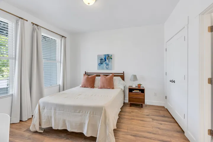 Recessed lighting, wood-finish flooring, white walls, multiple windows with blinds, and a white interior door with dark hardware