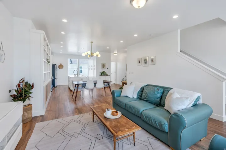 Open-concept living area featuring wood-finish flooring, recessed lighting, a built-in shelving unit, and a modern dining chandelier